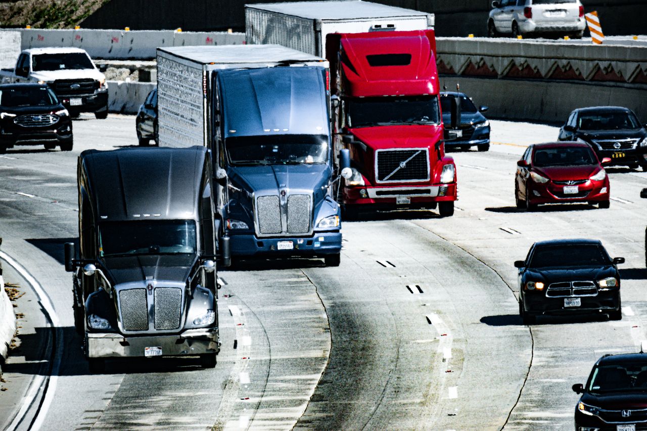 Trucks and cars traveling on a congested city highway during the day.